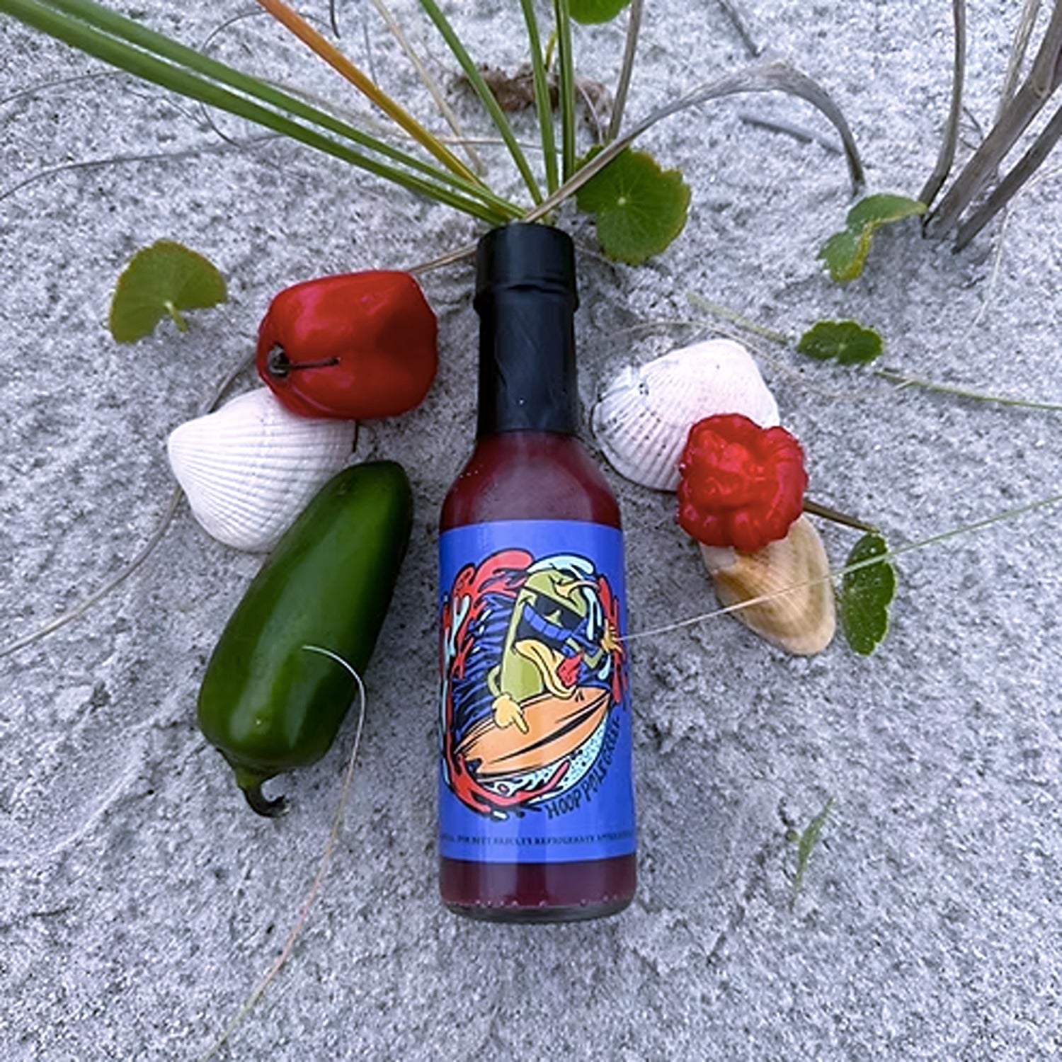 Bottle of Blueberry Habanero Hot Sauce with a rich, deep purple hue, surrounded by fresh blueberries and vibrant orange habanero peppers.