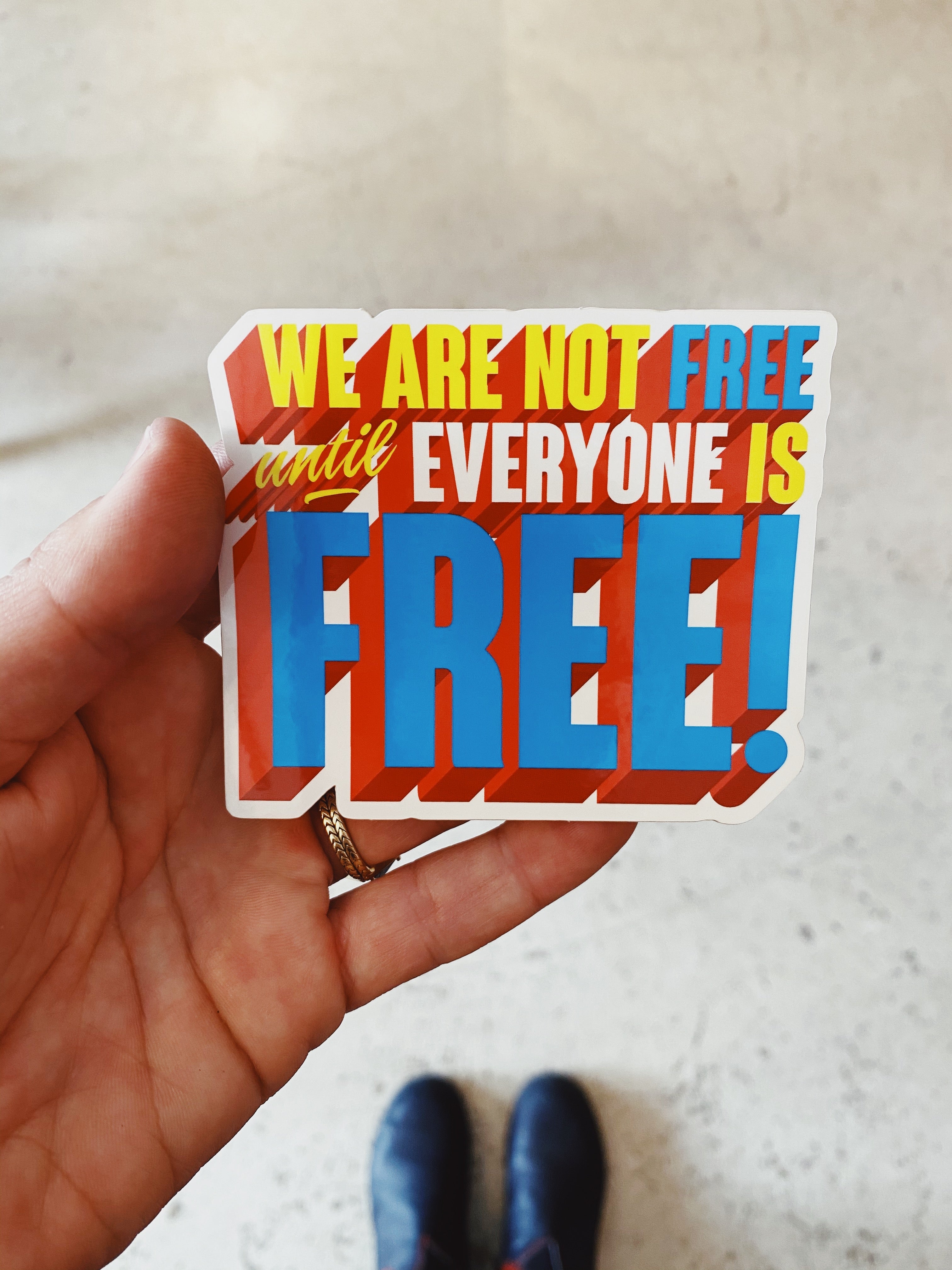 Sticker with the phrase 'We Are Not Free Until Everyone Is Free' in bold letters, symbolizing solidarity and the fight for freedom and equality for all.