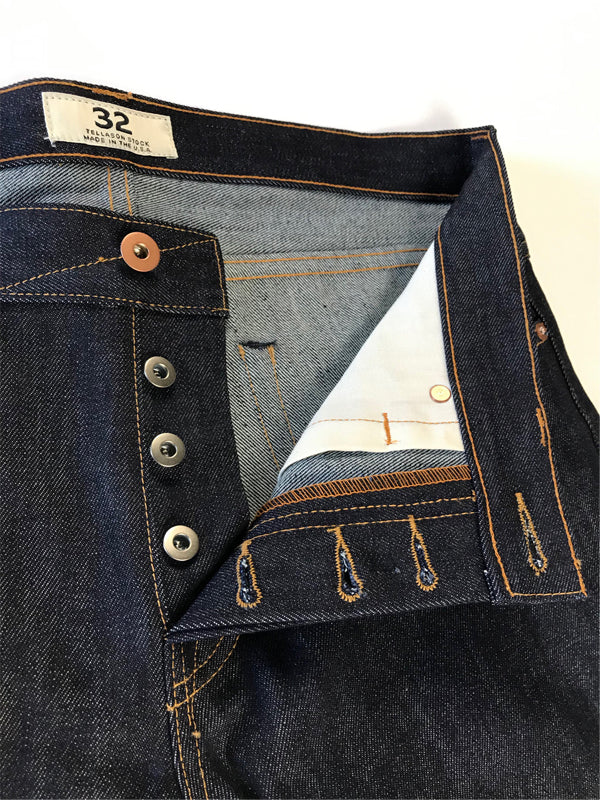 A pair of slim tapered jeans in a classic denim wash, featuring a sleek, fitted silhouette that narrows at the ankle, designed for a modern, stylish fit.