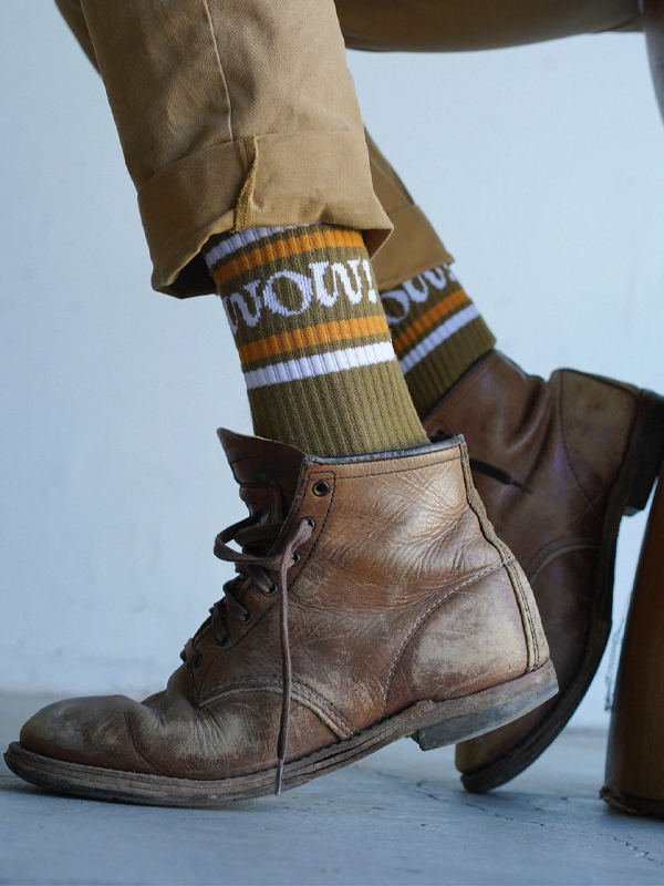 Pair of olive-green socks with the word 'Wow!' embroidered in bold, stylish lettering.