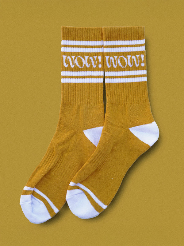Pair of mustard-yellow socks with the word 'Wow!' embroidered in bold, stylish lettering.