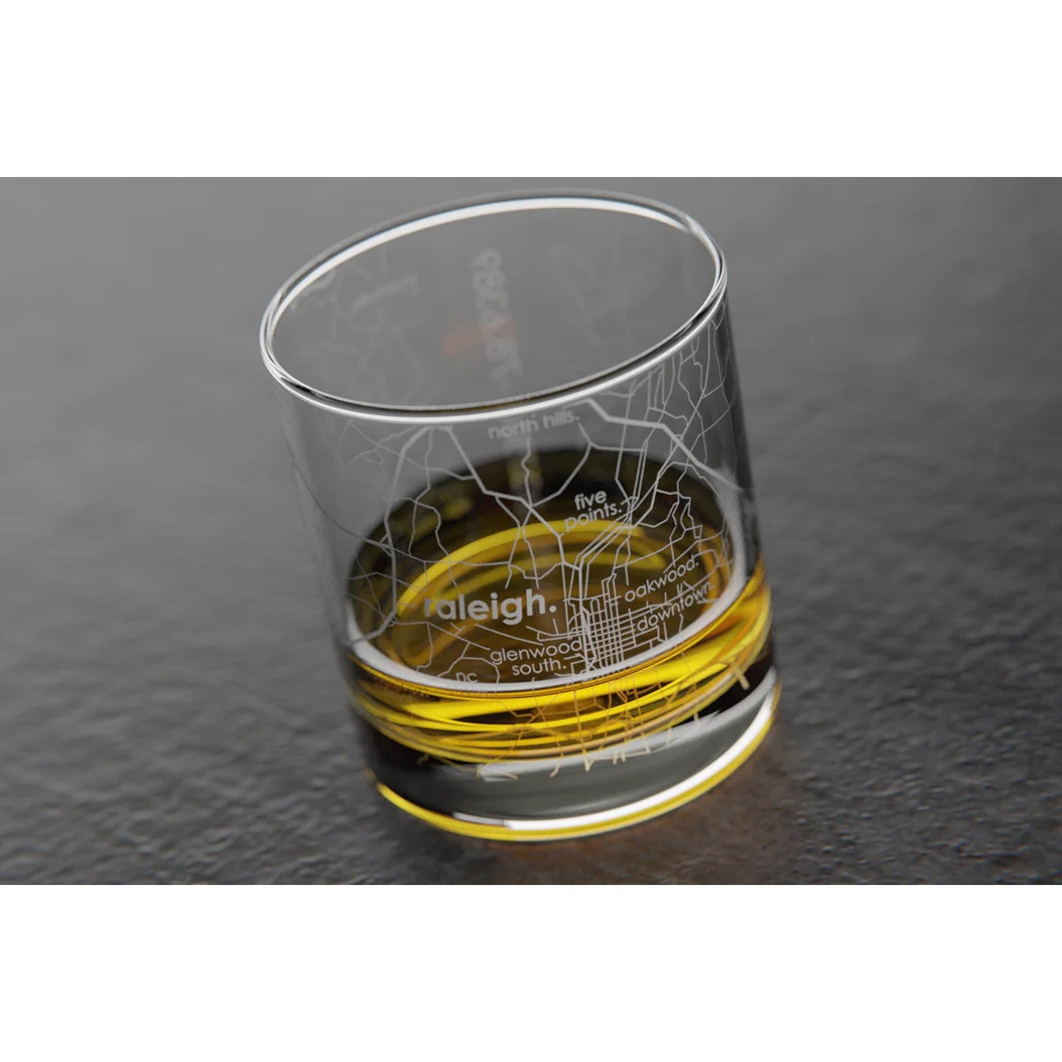 Rocks whiskey glass featuring an etched map of Raleigh, North Carolina, with streets and landmarks, perfect for sipping whiskey while celebrating the city.