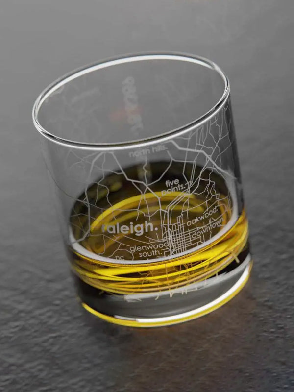 Rocks whiskey glass featuring an etched map of Raleigh, North Carolina, with streets and landmarks, perfect for sipping whiskey while celebrating the city.