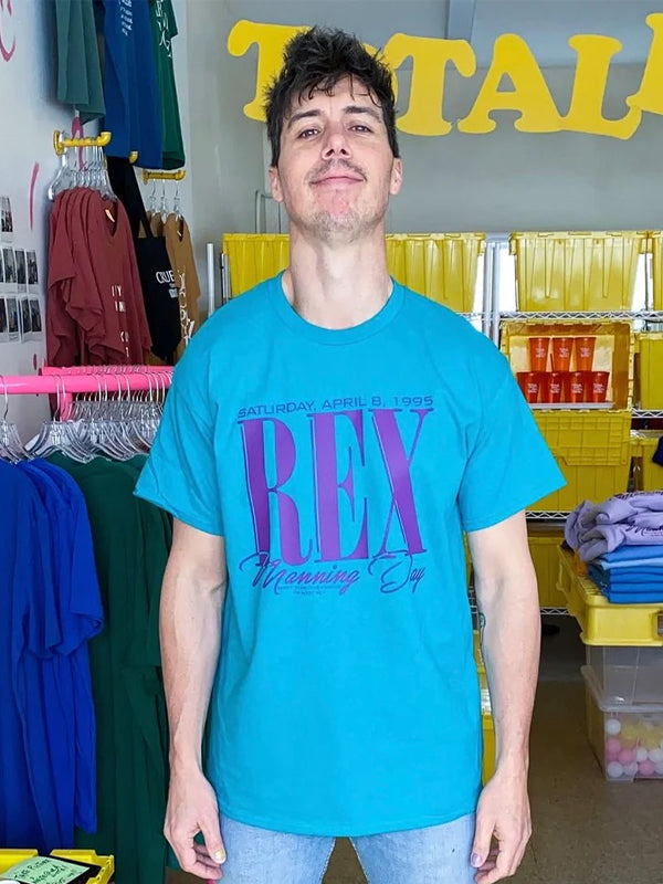 An "Empire Records Rex Manning Day" staff tee, featuring a vintage-style design inspired by the iconic film Empire Records, with bold text and a nod to the memorable Rex Manning Day celebration.