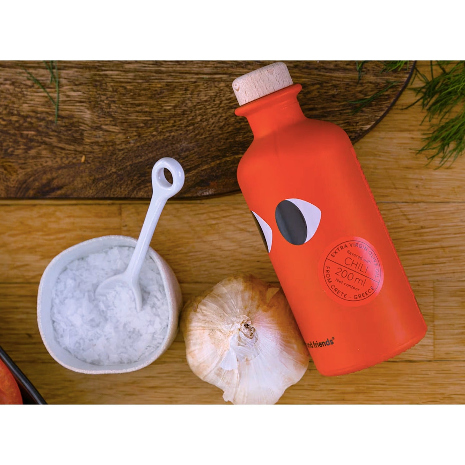 A bottle of Yiayia & Friends Extra Virgin Olive Oil infused with chili pepper, offering a spicy and flavorful kick for cooking and drizzling over dishes.